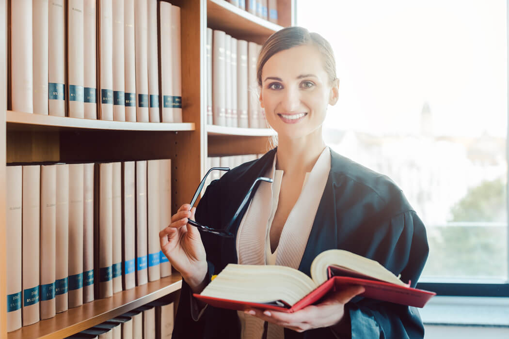 Junge Anwältin vor Bücherwand.